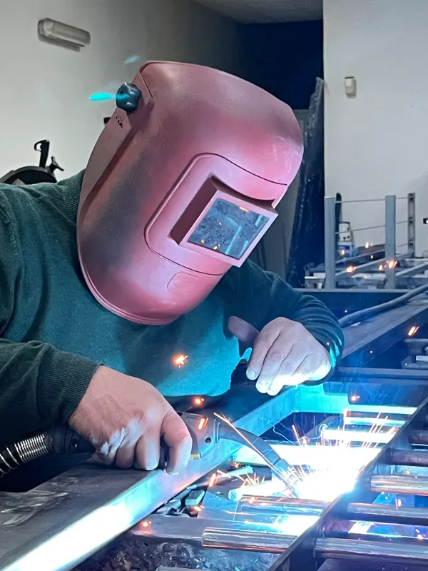 Enzo che esegue una saldatura su componente metallico